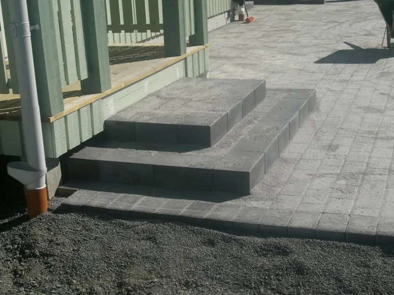 Trappa och stensättning i grå betongsten vid ett hus